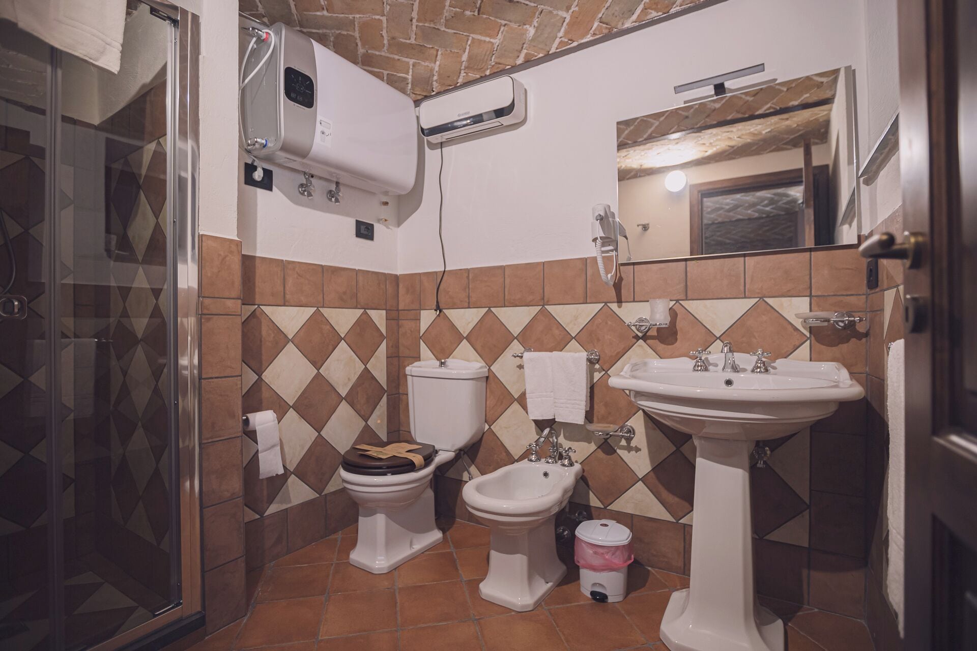 A bathroom with a shower, toilet, bidet, sink, and a towel rack.