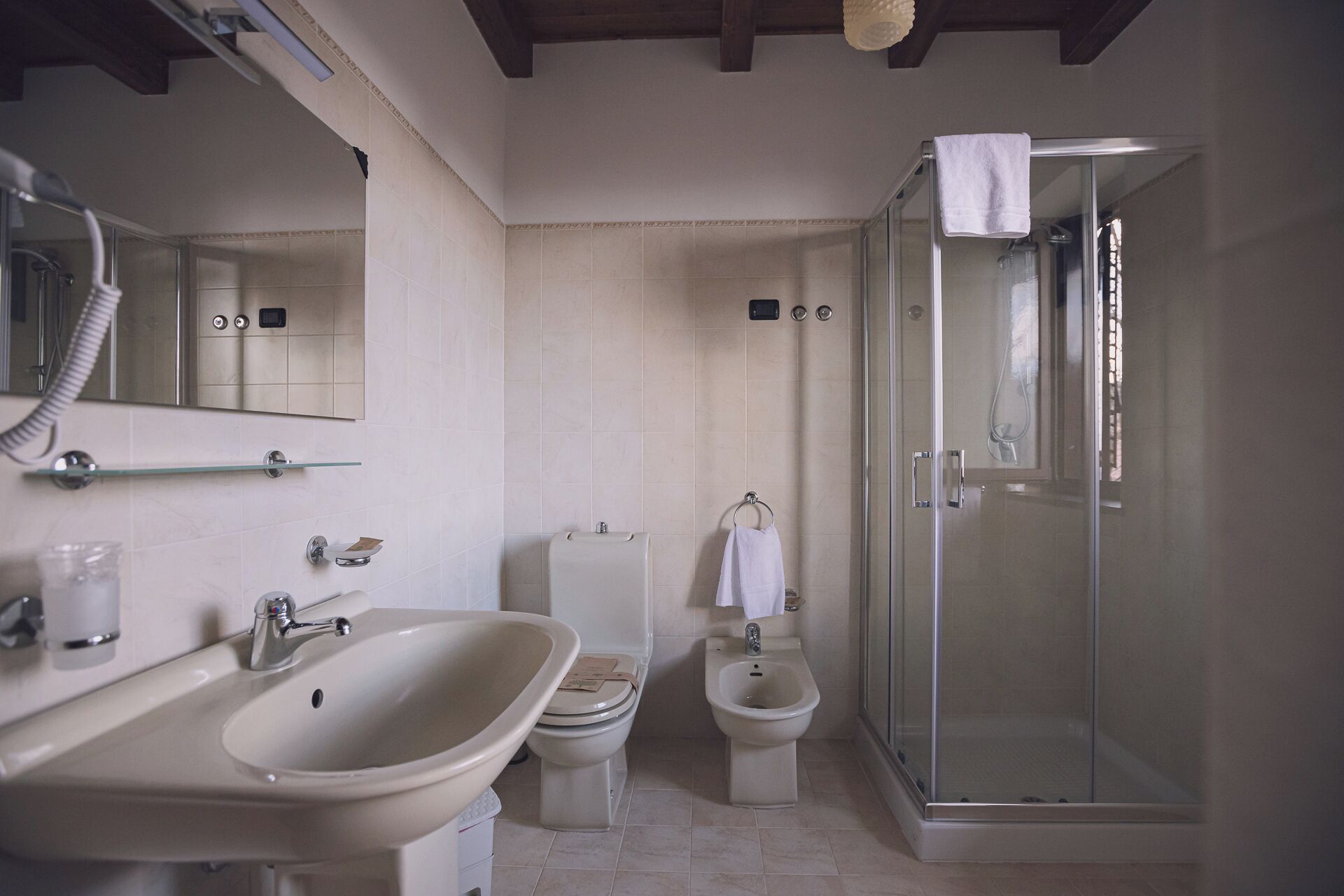 A bathroom with a sink, toilet, bidet, and a glass-enclosed shower.