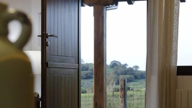 Una habitación con puerta de madera que da a una vista de paisaje rural.
