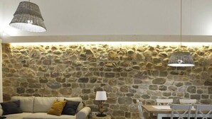 A cozy living area with a stone wall, a sofa, a round coffee table, and a dining table with chairs.