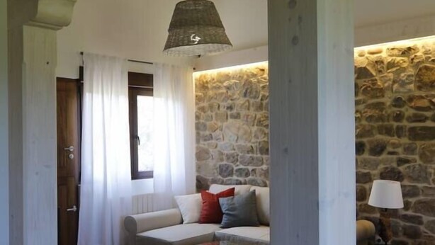 A cozy living room with a stone wall, a sofa, a round coffee table, and a hanging lamp.