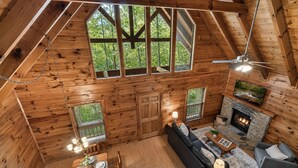 A log cabin interior with a dining area, sofa, fireplace, and large windows. - Top Location!Easy Drive-Hot Tub-Fire Pit-Games (Pigeon Forge)