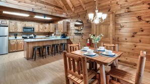 A wooden cabin interior with a kitchen, dining area, and bar. - Top Location!Easy Drive-Hot Tub-Fire Pit-Games (Pigeon Forge)