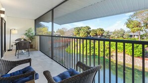 A balcony with wicker furniture, a table, and a lamp. - F-338 -Beautiful Resort and Sunset Views! (Naples)