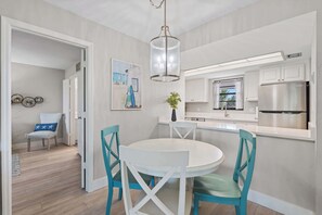 Una cocina moderna con armarios blancos, un refrigerador de acero inoxidable y una lámpara colgante.