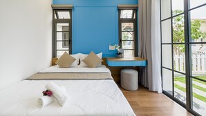 A bedroom with a large bed, a desk, and a view of the outdoors.