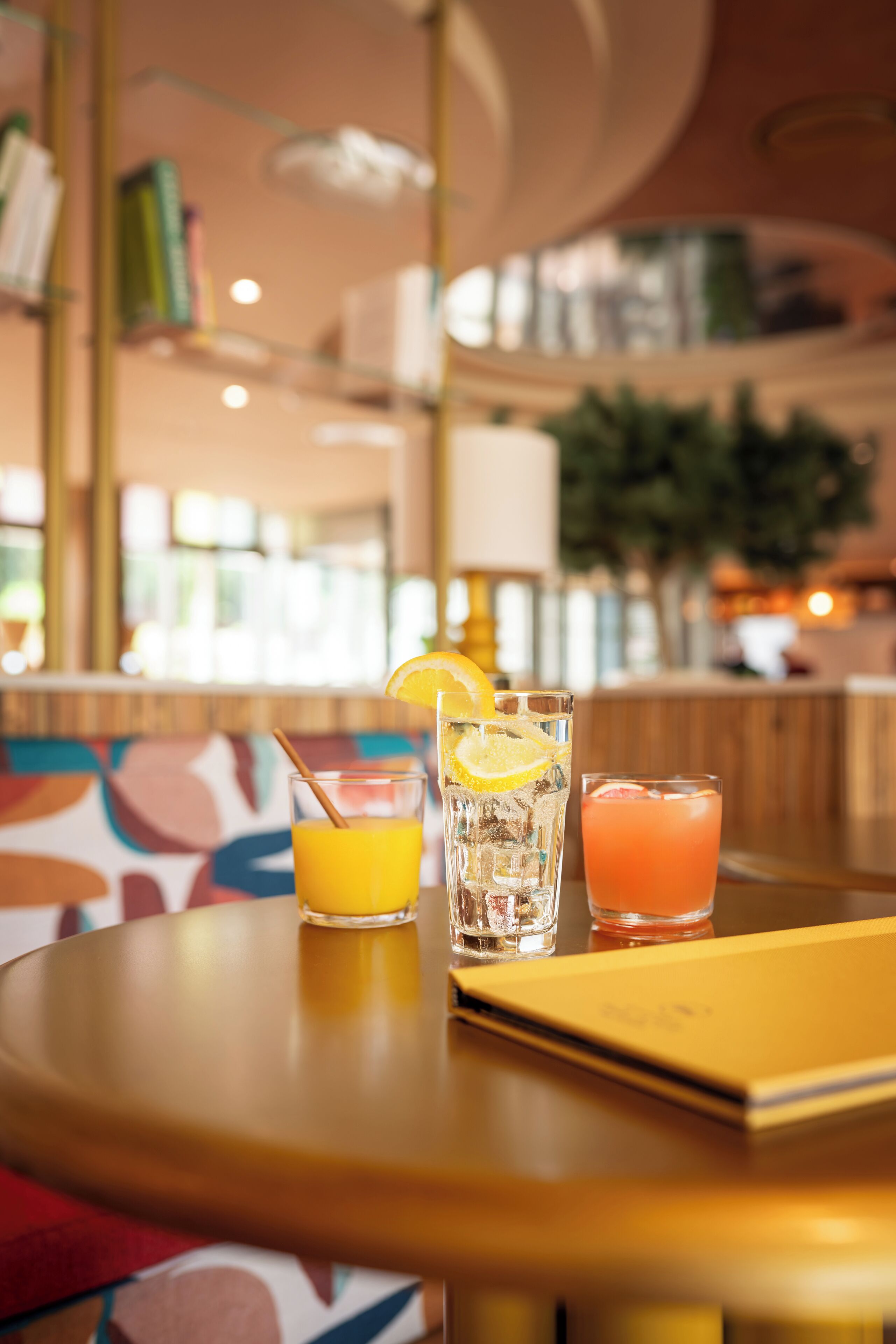 A bar area with two glasses of beverages, one with a straw and lemon slice, and another with a straw and orange slice.