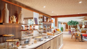 A buffet area with various food items and a seating area with chairs and tables.