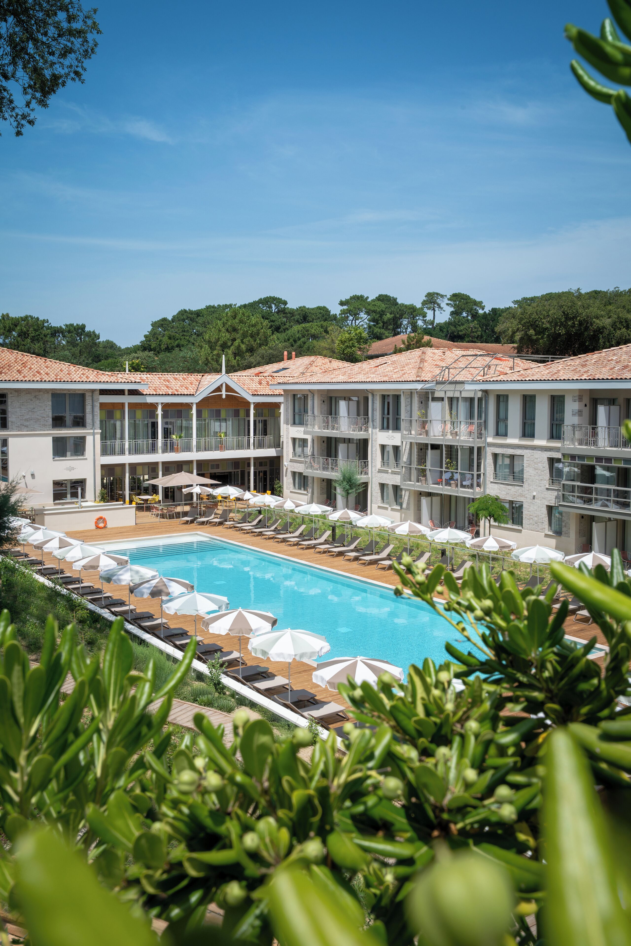 Un hotel con piscina, varios balcones y zonas de estar al aire libre.