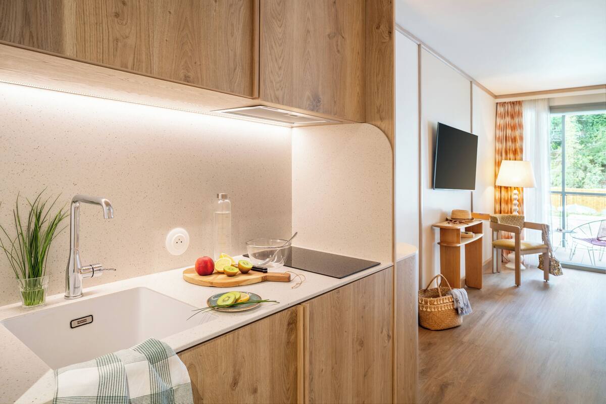 Eine moderne Küche mit einem Holzkasten, einer Edelstahl-Spüle und einem Schneidebrett mit Früchten.