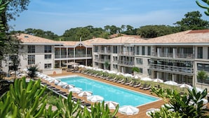 A hotel with a swimming pool, sun loungers, and umbrellas.