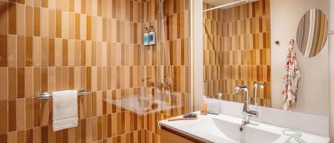 Un baño moderno con ducha, lavabo y espejo.