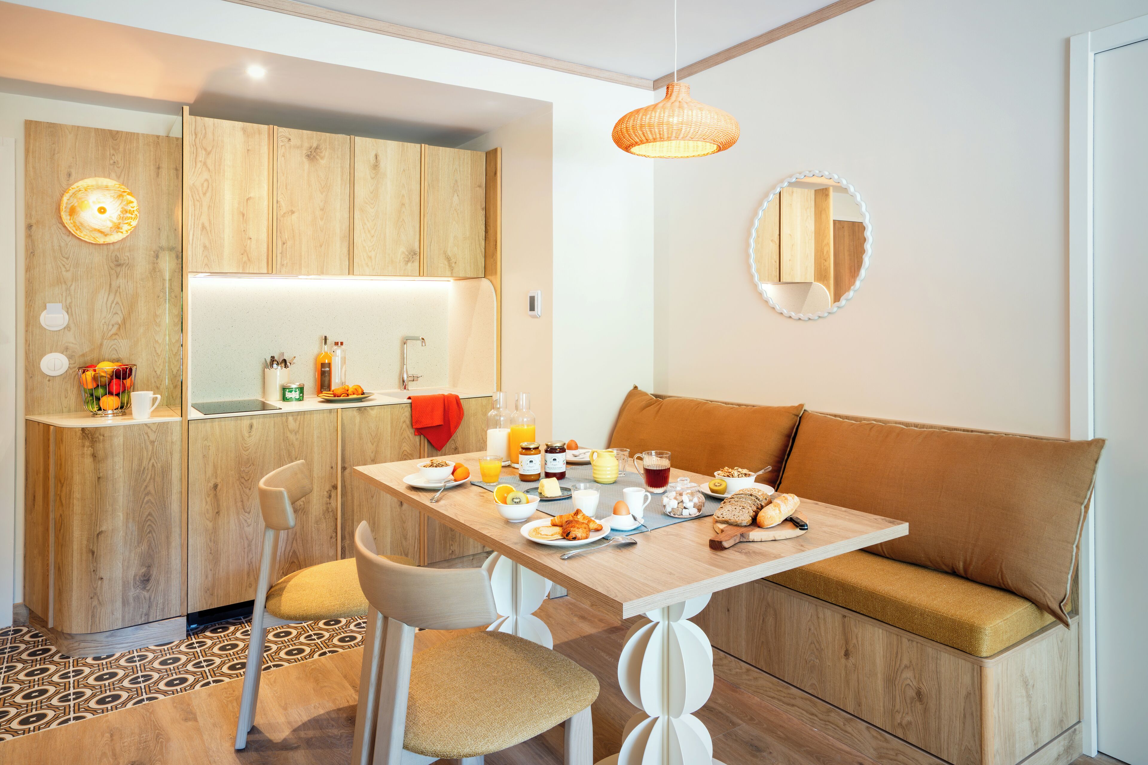 A modern kitchen with wooden cabinets, a dining table, and a bench.