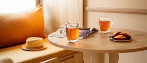 A cozy seating area with a round table, two glasses of tea, a book, and a hat.