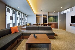 A modern living room with a sofa, a coffee table, and a dining area with a kitchen in the background. - Minn Karasuma Gojo Kyoto Station (Kyoto)