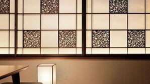 Una habitación con una mesa baja, un banco acolchado y un puertas correderas japonesas tradicionales con diseños intrincados.