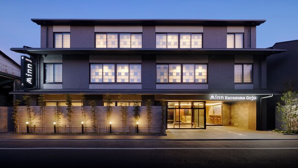 Un hotel moderno con fachada de dos pisos, ventanas amplias y una entrada bien iluminada.