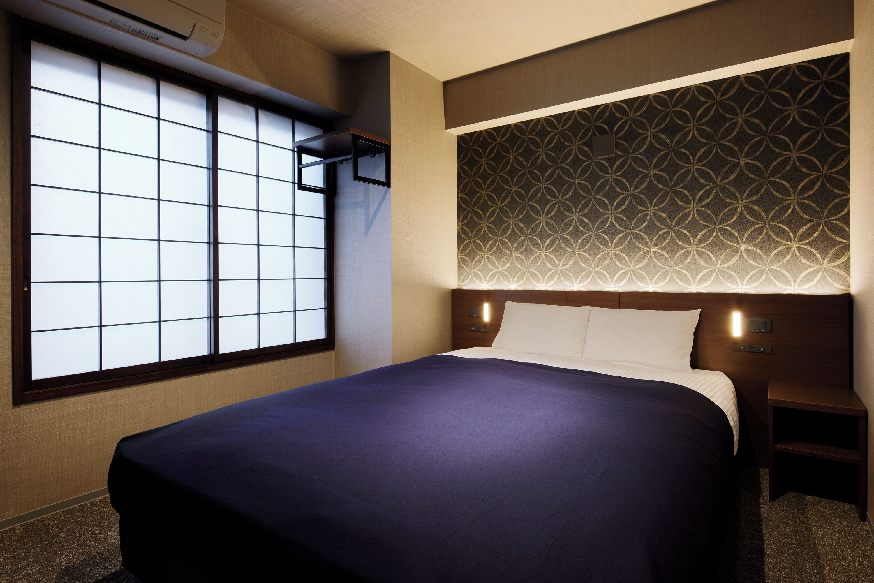 Una habitación de hotel con una cama grande, una ventana con diseño de cuadrícula y un panel decorativo en la pared.