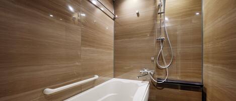 A modern bathroom with a large bathtub, a glass shower enclosure, and wooden walls.