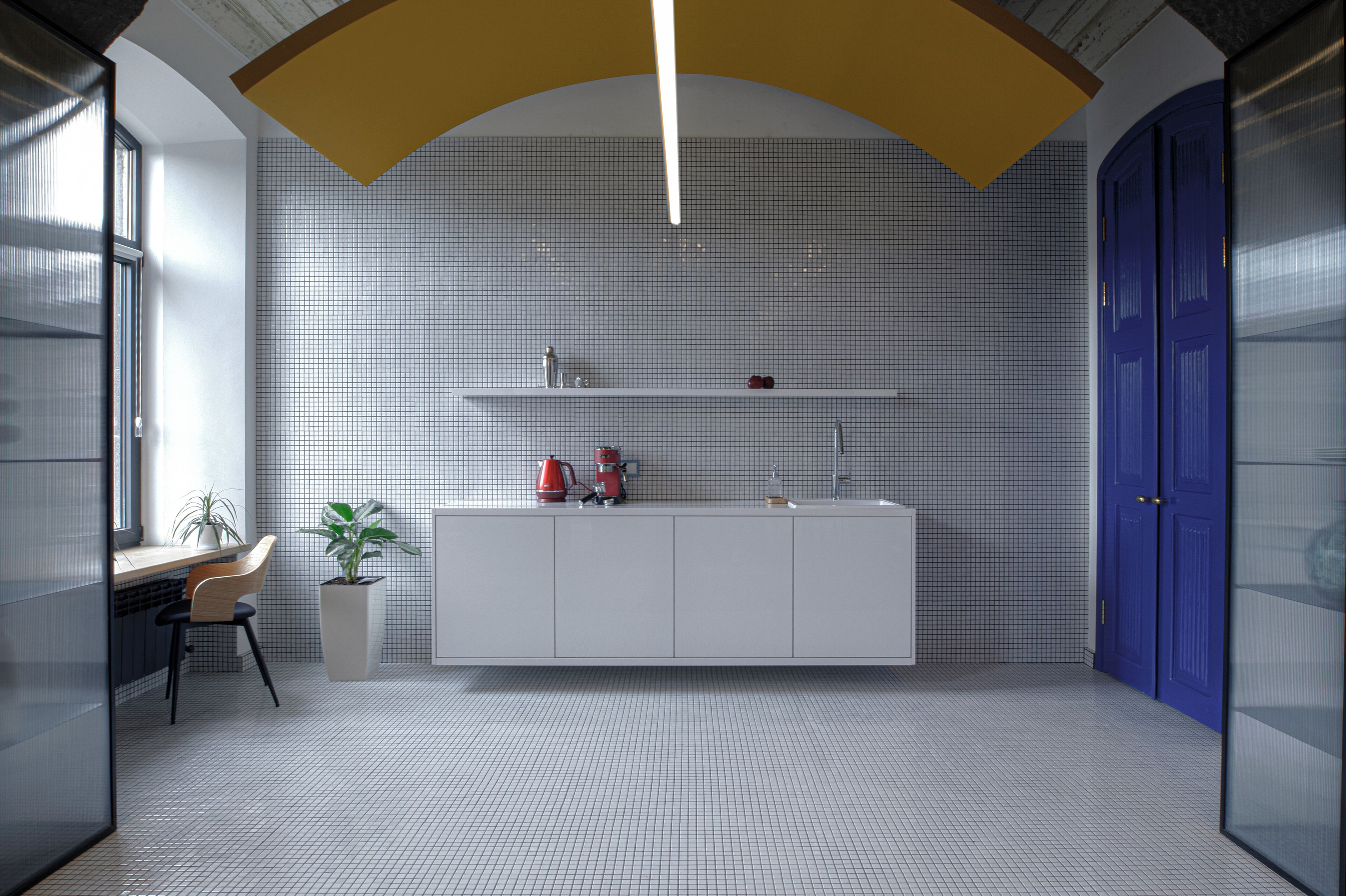 A modern kitchen with white cabinets, a countertop, and a potted plant.
