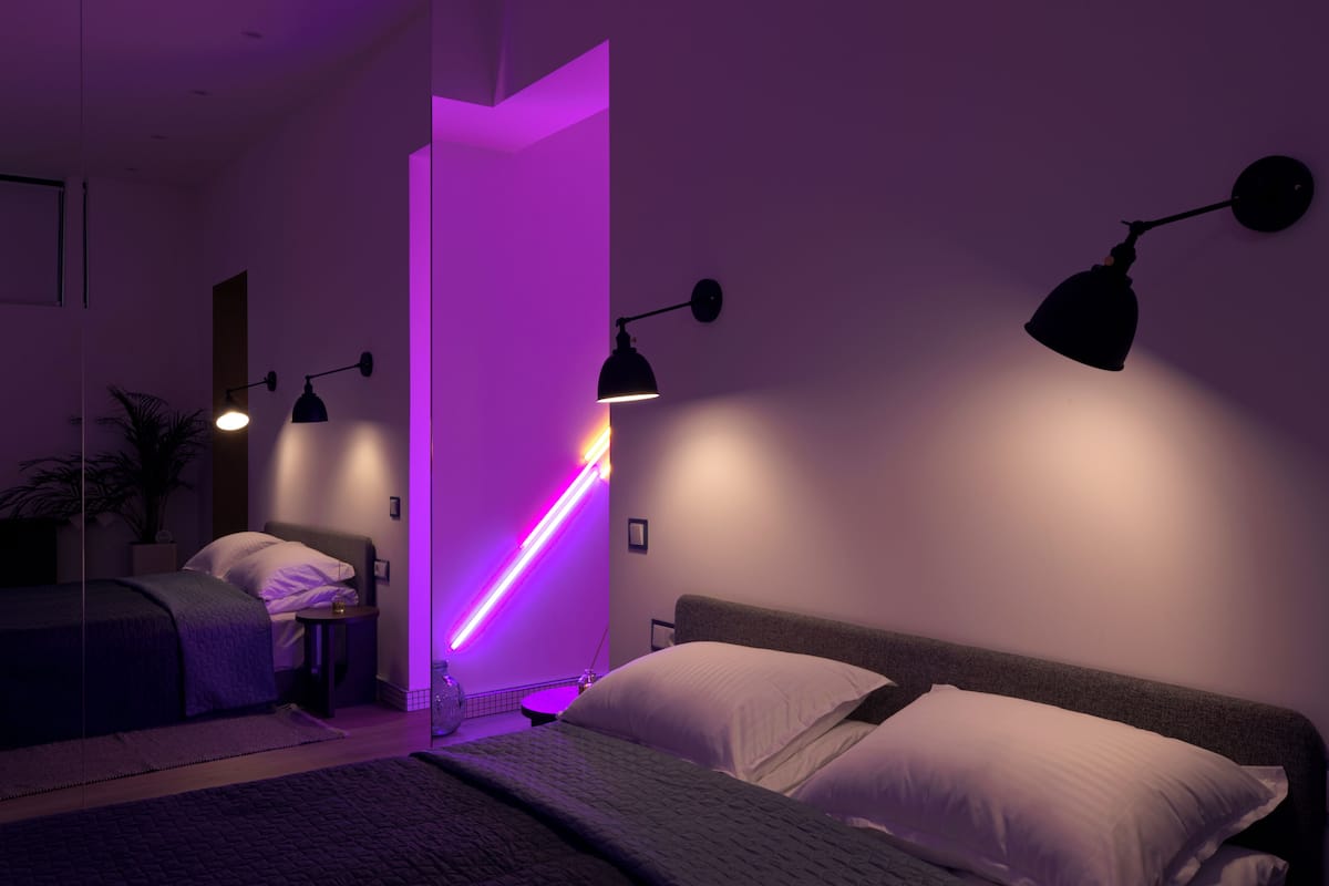 A modern bedroom with a bed, bedside tables, and wall-mounted lamps.