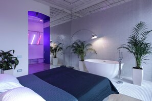 Un dormitorio moderno con una cama grande, una bañera blanca y varias plantas en macetas.