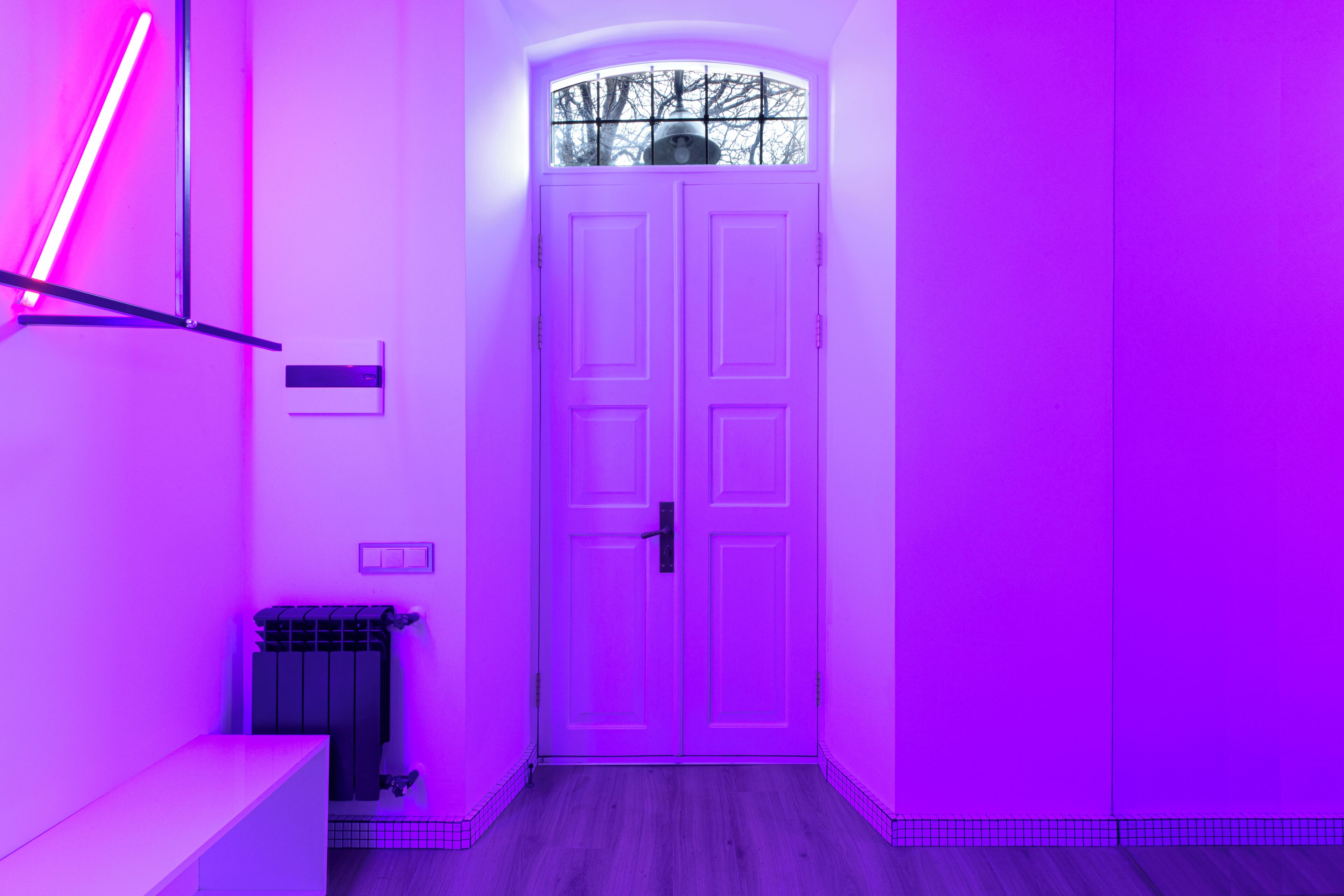 A hallway with a double door, a bench, and a radiator.