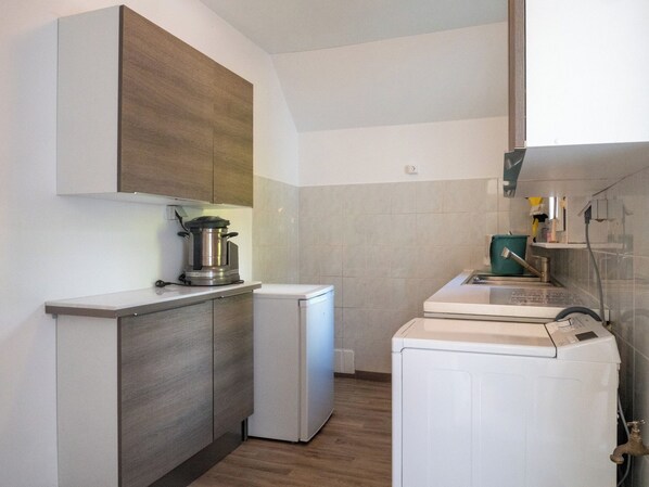 A compact kitchen with a built-in stove, a small refrigerator, and a washing machine. - Superb house 100m from the sea with heated swimming pool (Concarneau)