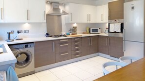 A modern kitchen with white cabinets, a built-in stove, a microwave, and a refrigerator.