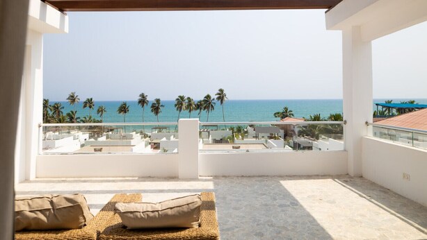 A balcony with a view of the sea and palm trees.