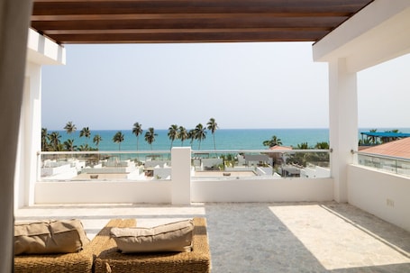 A balcony with a view of the sea and palm trees.