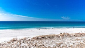 A beach with a clear sky, sandy shore, and a few people.
