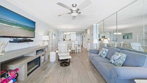 Ein modernes Wohnzimmer mit Flachbildfernseher, Deckenventilator, Kamin, Sofa und Essbereich.