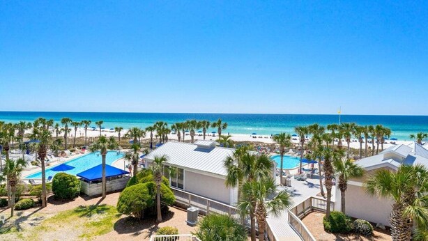 Un resort con piscina, playa y palmeras.