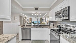 A modern kitchen with white cabinetry, a stainless steel dishwasher, a built-in oven, and a microwave.