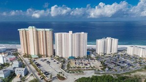 A coastal hotel complex with multiple high-rise buildings, a parking lot, and a view of the ocean.