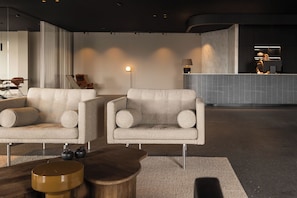 Een moderne lobby met twee fauteuils, een houten salontafel en een receptiebalie.