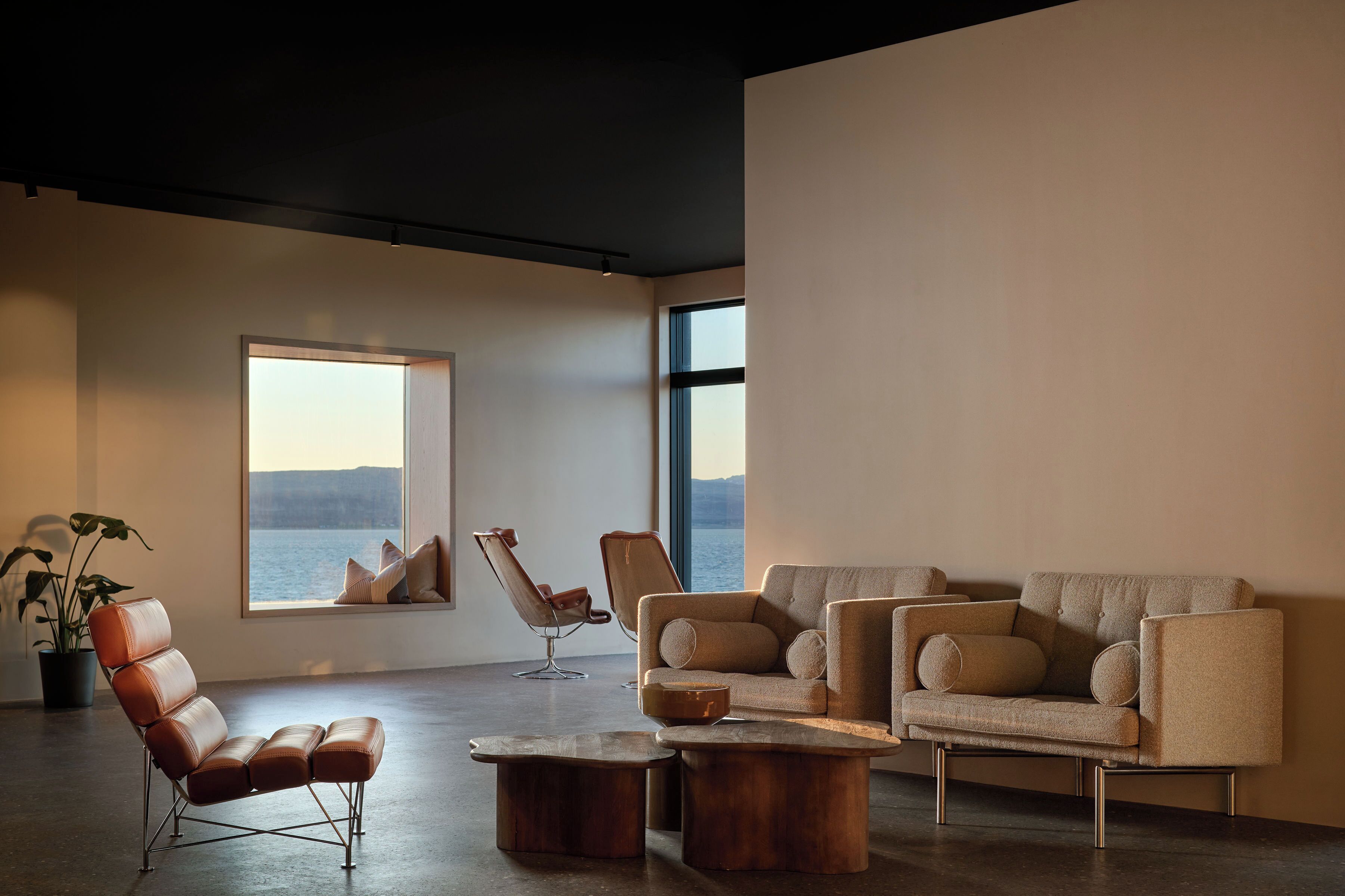 Una sala de estar moderna con un ventanal grande, sillones de cuero, un sofá y una mesa de centro de madera.