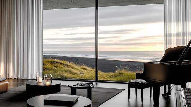 Un salon moderne avec un piano, un canapé, une table basse et une vue sur l’océan.