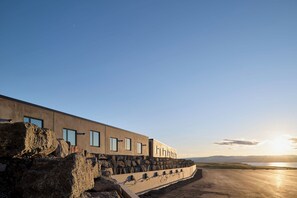 Een modern gebouw met een plat dak, grote ramen en een stenen steunmuur.