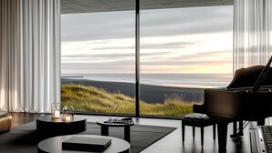 Un salon moderne doté d’une grande fenêtre, d’un piano et d’un aménagement minimaliste.