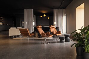 Een moderne zithoek met lederen fauteuils, een bank en een salontafel.