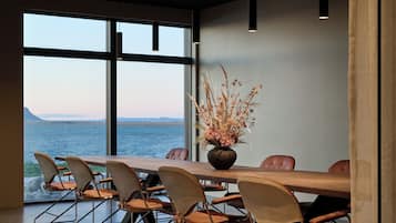 Un salón de conferencias con vista al mar, una mesa de madera y sillas modernas.
