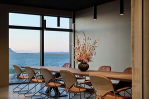 A conference room with a view of the sea, a wooden table, and modern chairs. - Black Sand Hotel (Sveitarfélagid Ölfus)