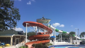 Un parco acquatico con uno scivolo a più livelli, una piscina e una torretta per i bagnini.