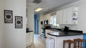 Una cucina moderna con mobili bianchi, un piano di lavoro nero e un'isola con sgabelli.
