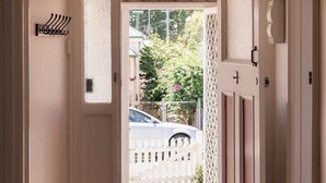 A hallway with a white door leading to a balcony, a hanging light fixture, and a patterned rug on the floor. - 'Sobrina' - A home away from home in Sandy Bay (Sandy Bay)
