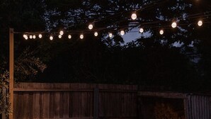 An outdoor seating area with wooden benches and a fire pit, surrounded by a wooden fence and string lights. - 'Sobrina' - A home away from home in Sandy Bay (Sandy Bay)
