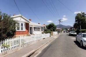 A residential street with houses, a white picket fence, and parked cars. - 'Sobrina' - A home away from home in Sandy Bay (Sandy Bay)
