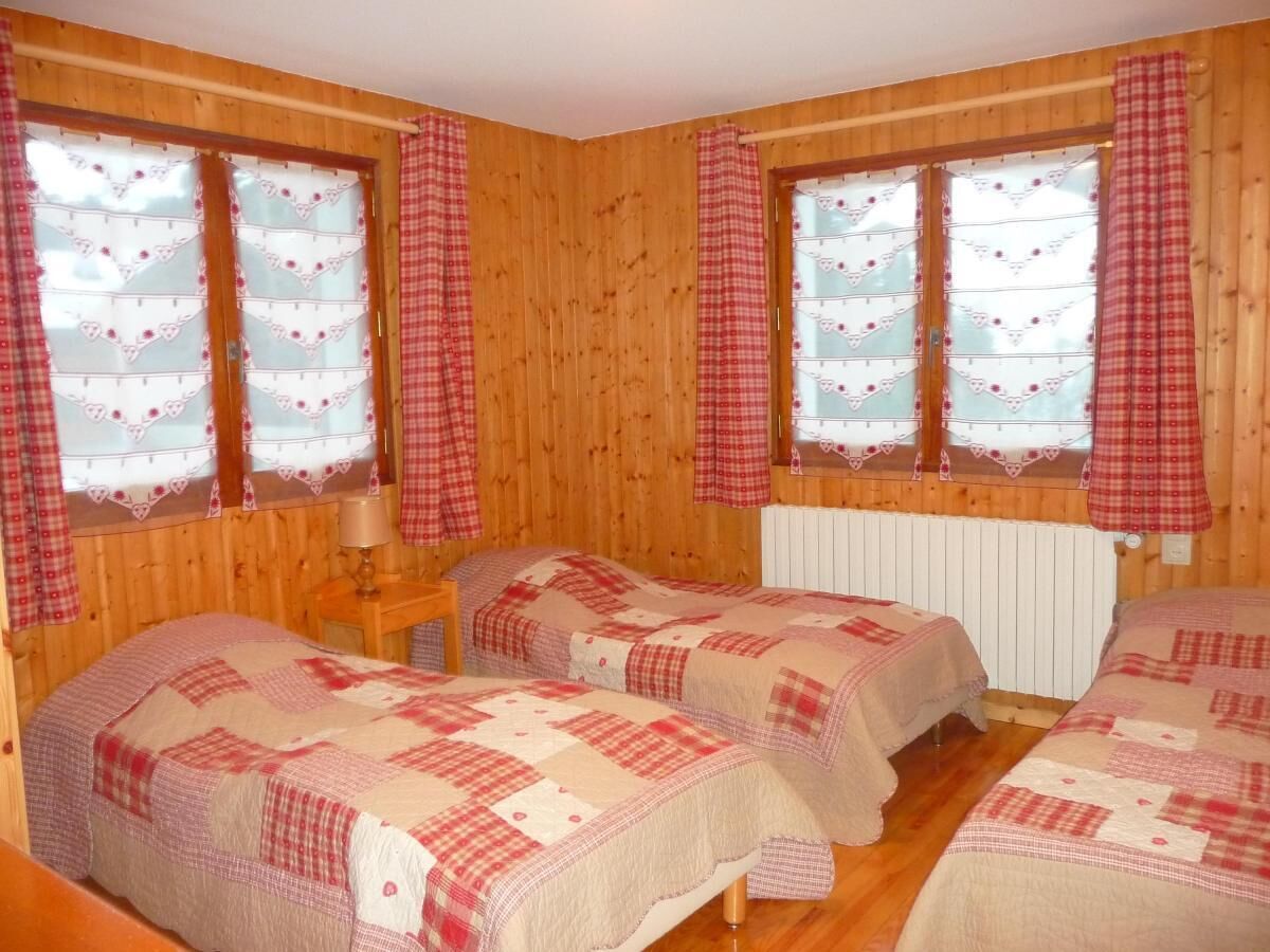 Une pièce aux murs en bois, avec deux lits recouverts de draps à carreaux.